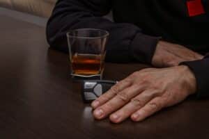 Driver holding alcohol flask behind the wheel in Dallas drunk driving accident case involving negligence and serious injury liability claims