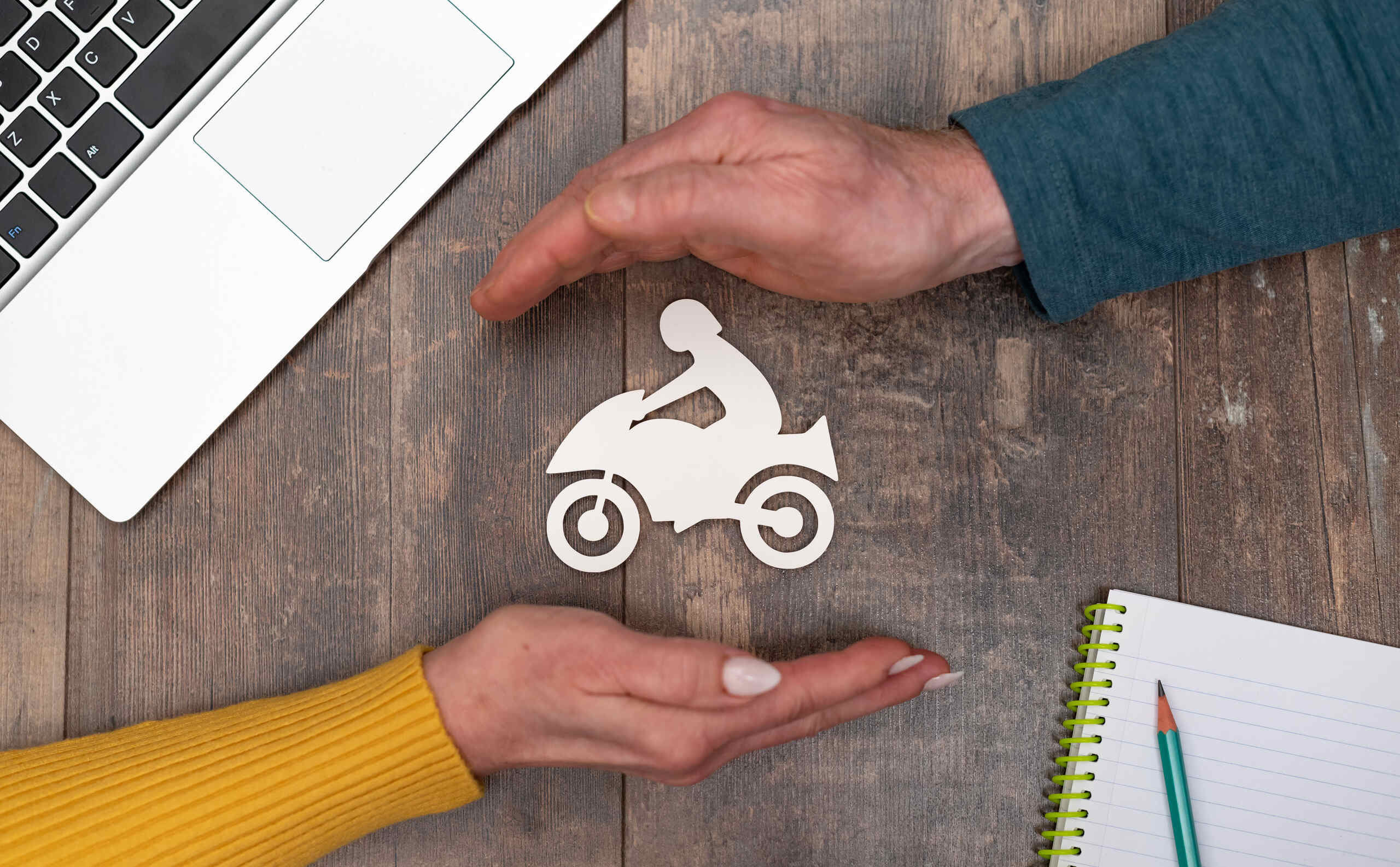 Hands protecting a motorcycle paper cutout reflecting Fort Worth motorcycle accident statistics.