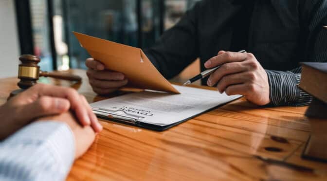 Abogado especializado en lesiones personales revisando un acuerdo de honorarios condicionales durante una consulta gratuita.