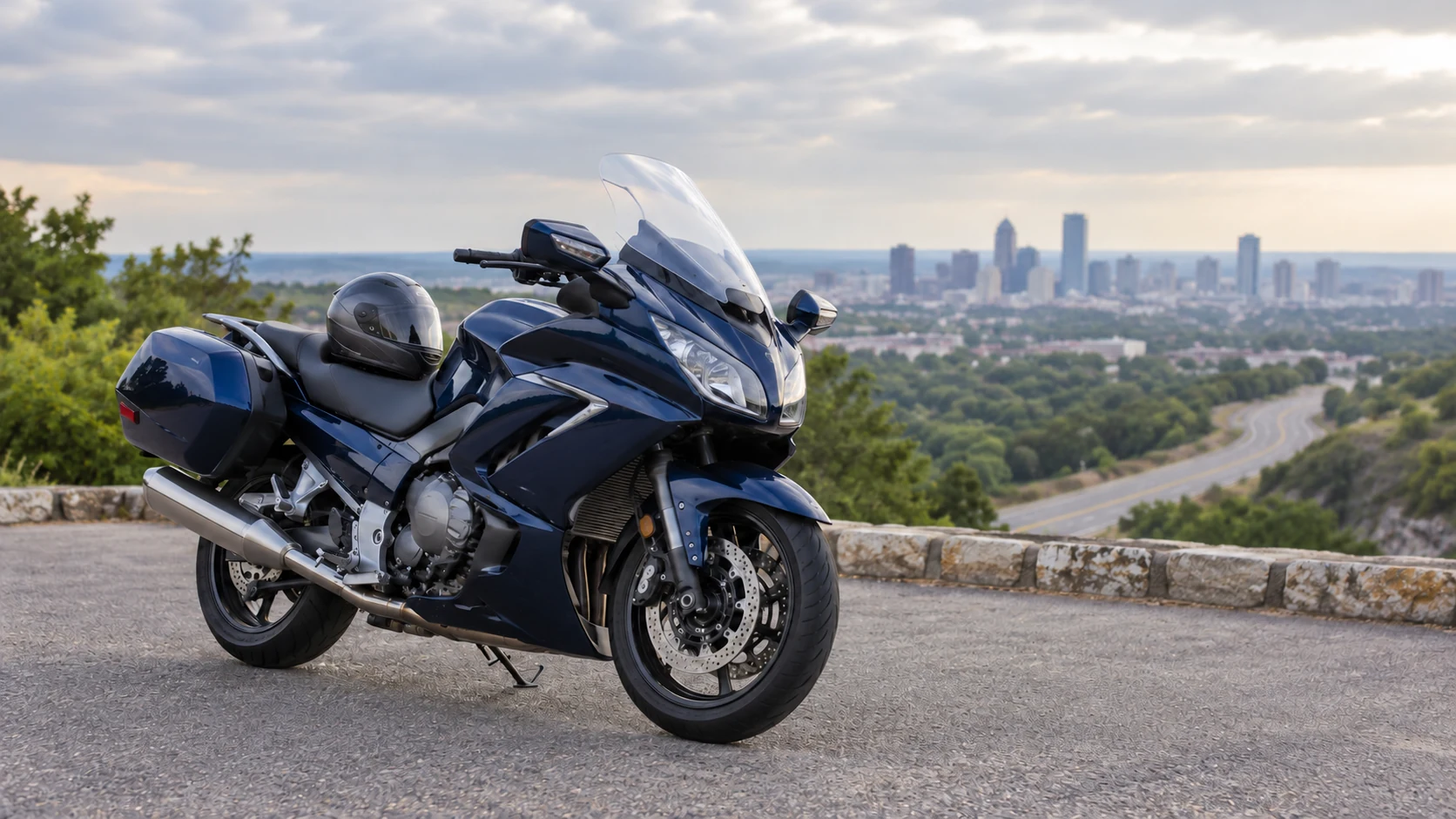 A navy motorcycle and full-face helmet at a roadside overlook.