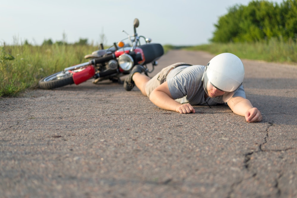 Dallas motorcycle accident lawyer highlighting injured rider lying on road after motorcycle crash with helmet and bike in background.