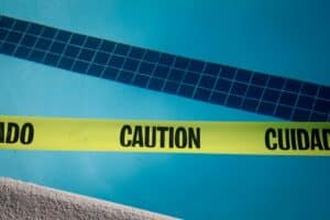 Swimming pool accident in Dallas with caution tape near pool highlighting slip hazard relevant to a San Antonio premises liability attorney.
