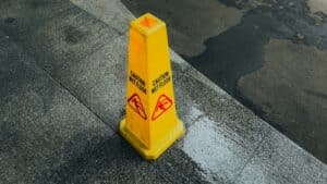 San Antonio premises liability attorney highlighting wet floor warning sign on sidewalk showing slip and fall hazard.