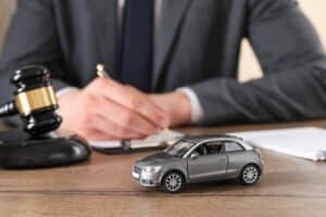 Dallas car accident lawyer discussing insurance claim and legal options after a vehicle crash with model car and gavel on desk.