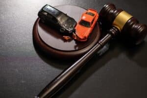 Dallas car accident lawyer image of gavel with damaged toy cars symbolizing legal case after crash
